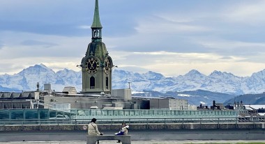 A photo of the city of Bern, with a large clock tower in front of snowy mountains