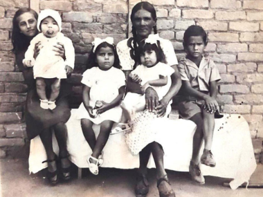 Old black and white photo of a family, described by the author: "At the center, my great-grandmother Maria holds my grandmother Derby on her lap, 1945, Governador Valadares, Minas Gerais, Brazil."