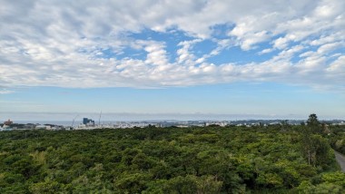 A landscape photo of a cloudy blue sky over the green shores and ocean of Okinawa