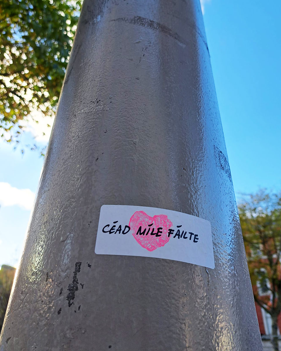 A sticker attached to a lamp post, with a heart and the words "Cead Mile Failte"