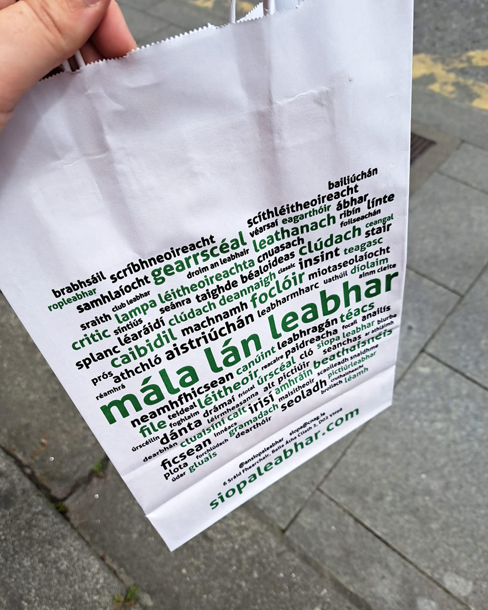 A white paper bag printed with Irish language text. 