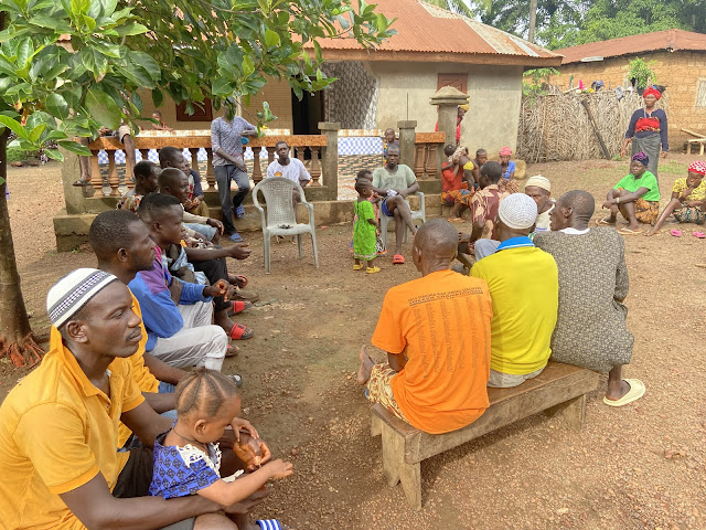A group of people gathered in front of a house in Moribaya Village, Sierra Leone