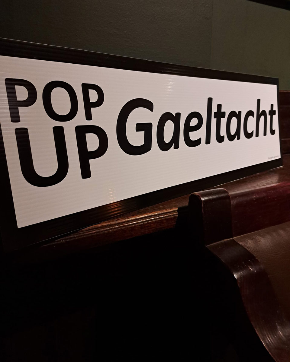 A white sign with black text reading "Pop up Gaeltacht"