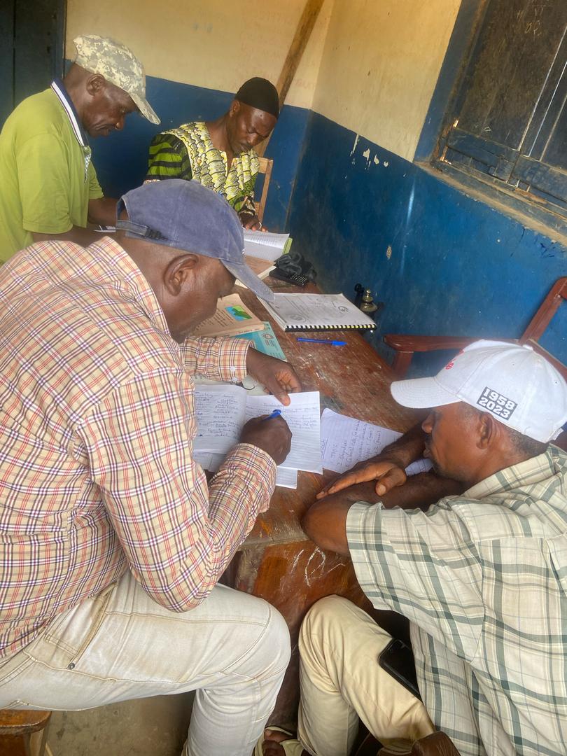 A group of men around a table writing in notebooks